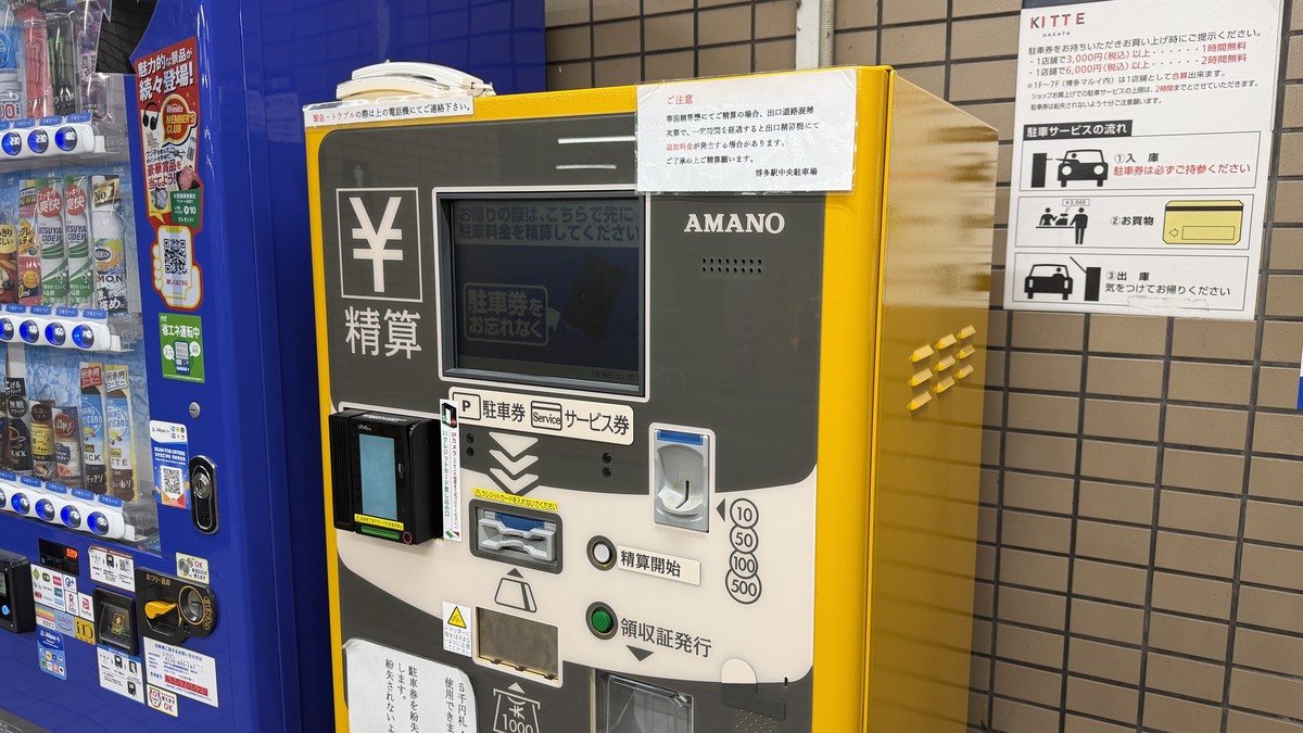 1階に設置された事前精算機(AMANO製)。事前精算後、出口が混雑して一定時間を超えると追加料金が発生する場合があるとの注意書きがあります。
