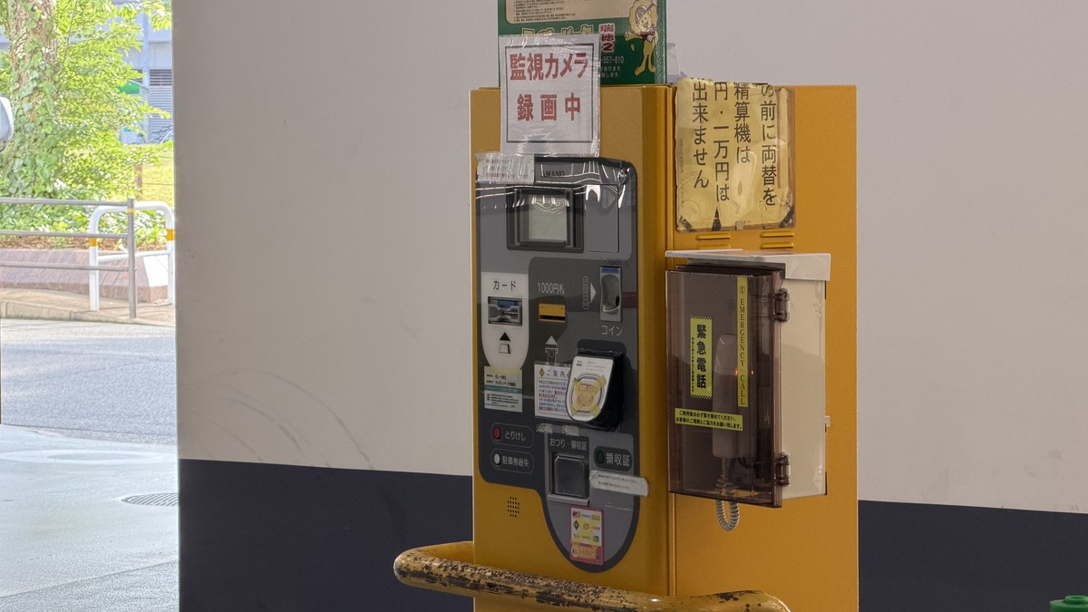 精算機。現金のみ対応(1,000円札以外の紙幣は使用不可)。緊急連絡用のインターホンも設置されています。
